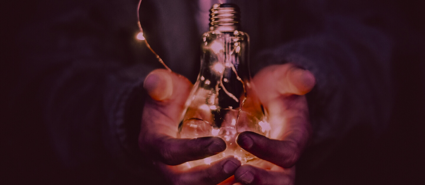 A child's hands holding an illuminated lightbulb